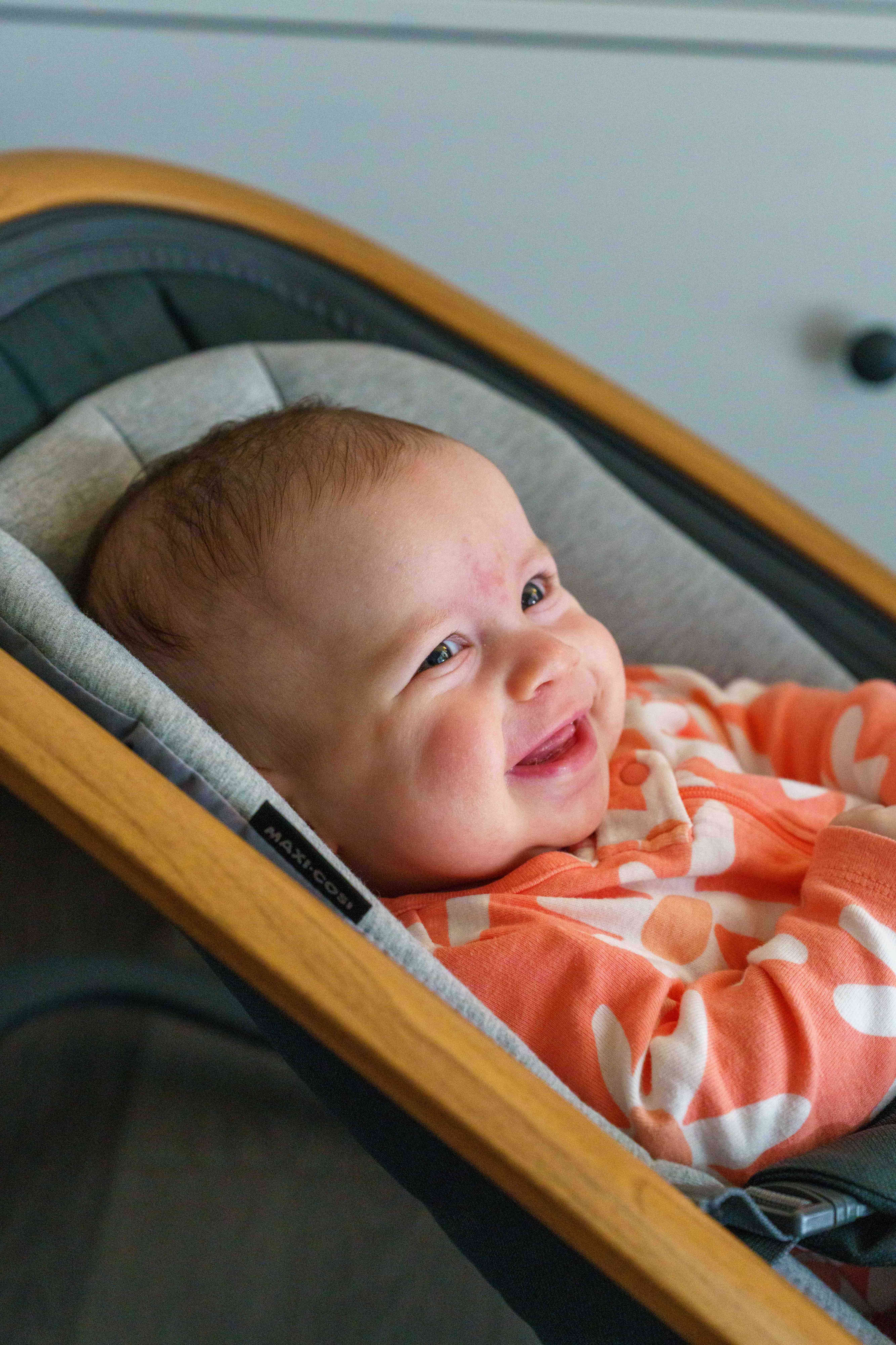 Isabella smiling in wooden bassinet